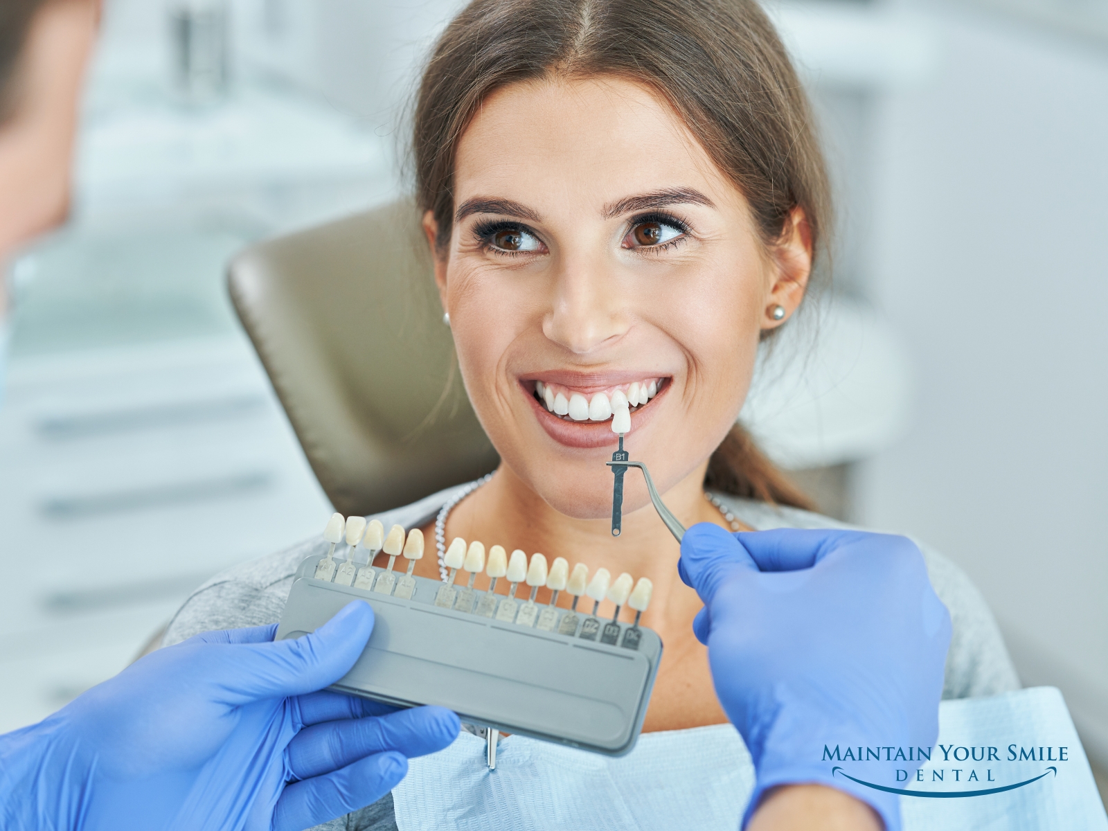 Cosmetic dentist at Maintain Your Smile in Rockford, IL, using a shade guide to show a patient her new, whiter smile after a professional teeth whitening treatment.